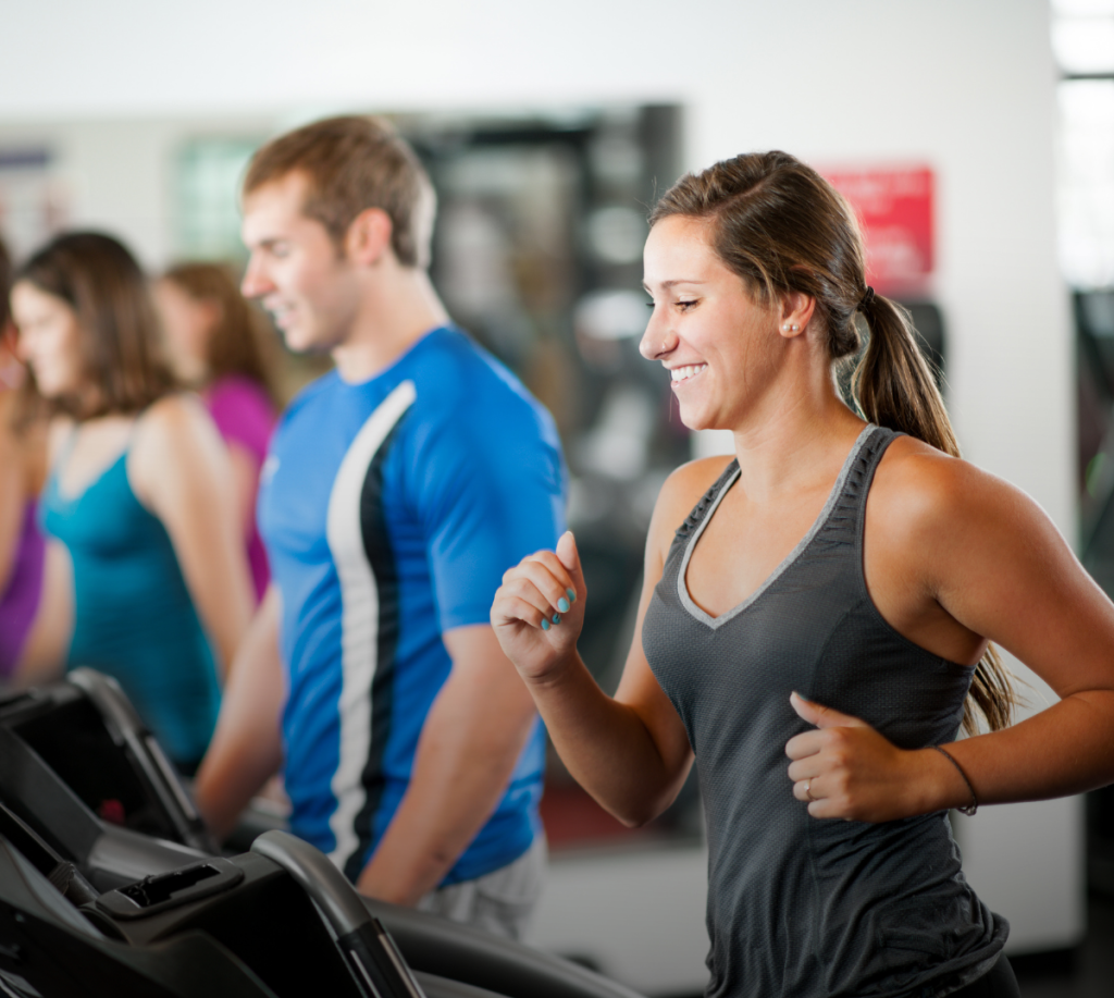 Flera personer tränar på löpband bredvid varandra på ett gym.