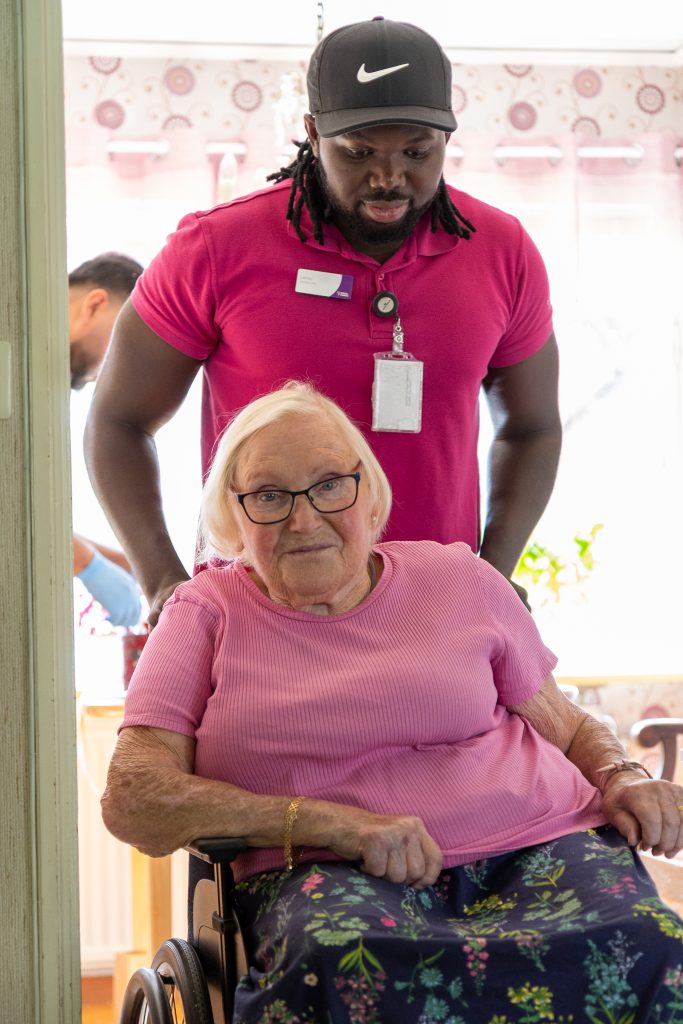 man kör äldre dam i rullstol