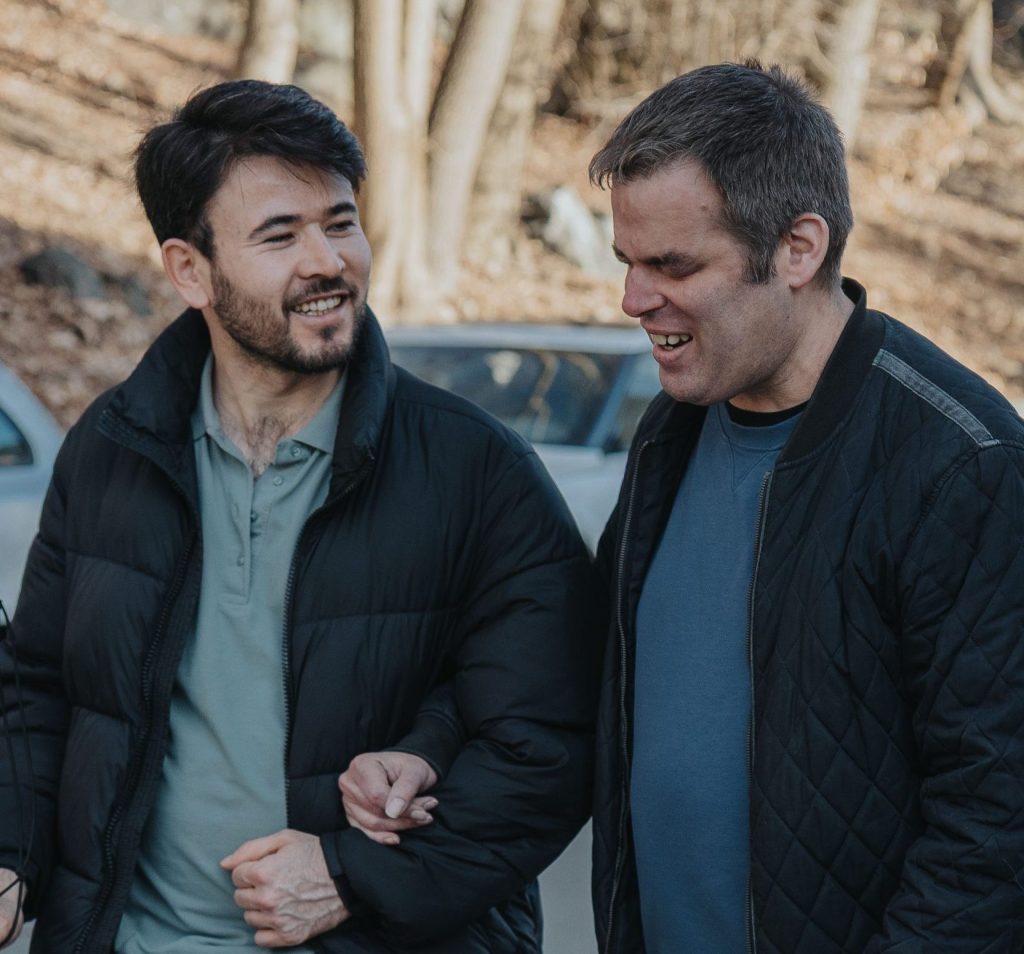 två leende gående män, en av dem blundar